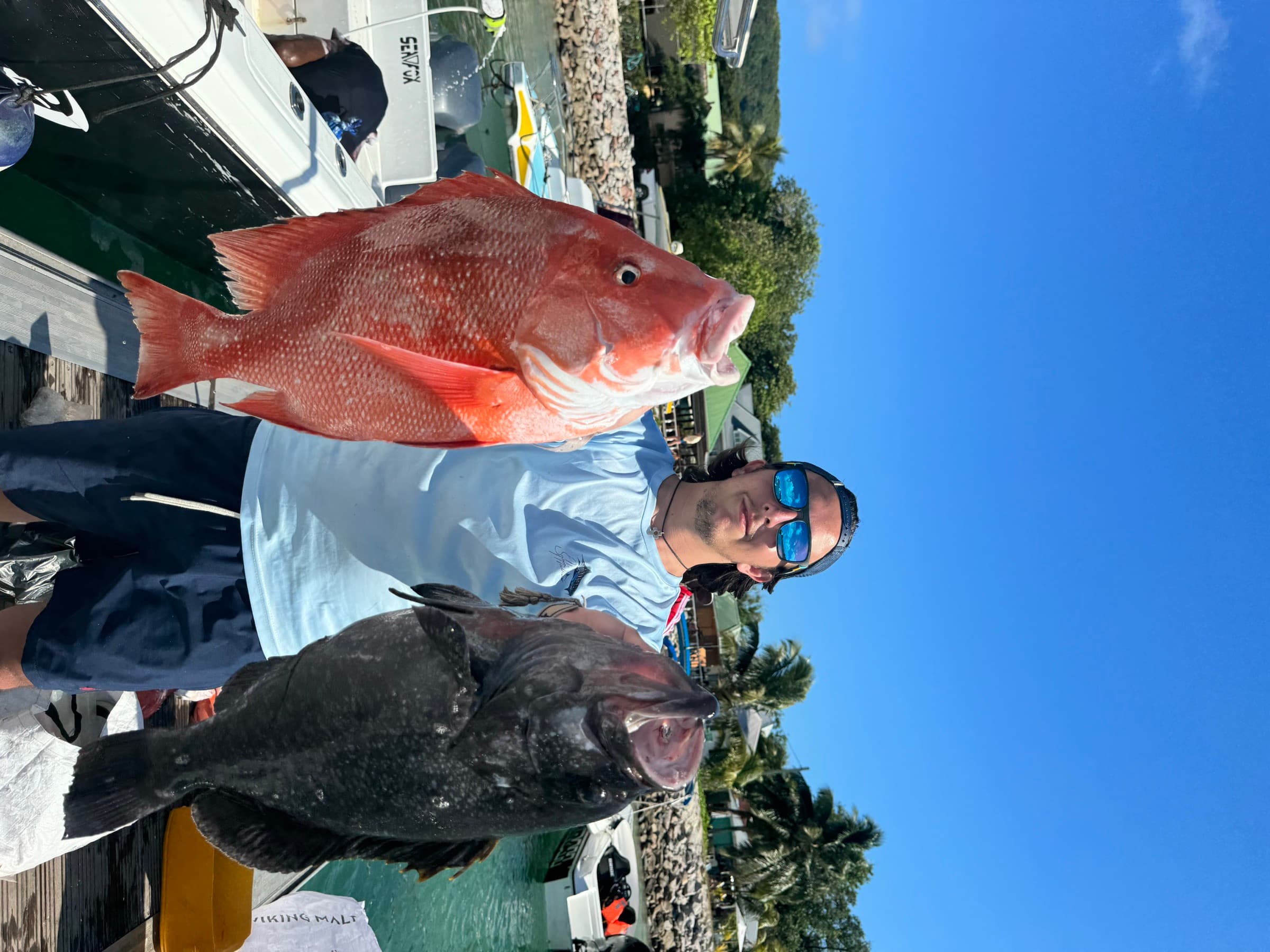 Angler holding a red snapper and grouper after a charter fishing day in Seychelles