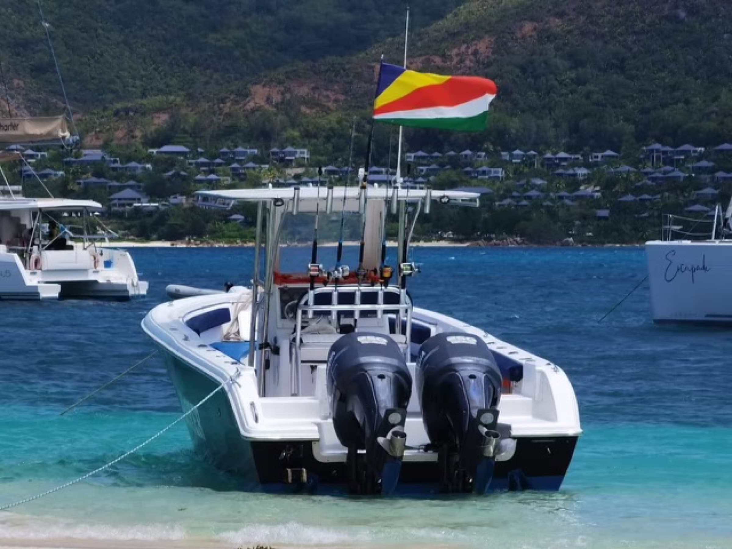Private boat charter at anchor in a La Digue cove, Seychelles flag flying